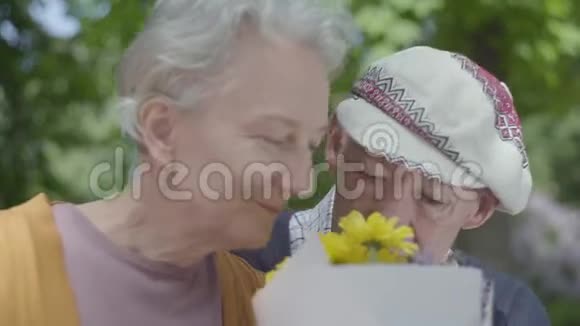 老夫妇白发的女人戴帽子的男人闻着黄花的味道说话成人夫妇视频的预览图