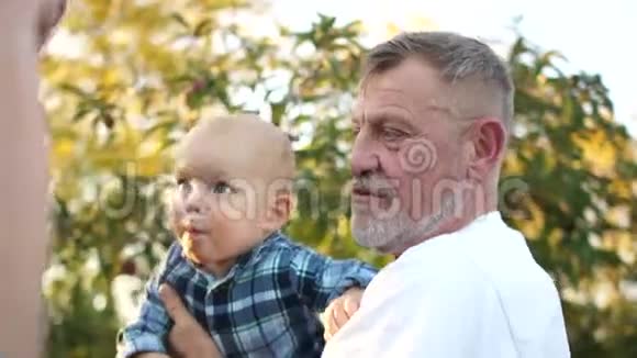 父亲挠他的儿子婴儿坐在他祖父的怀里快乐地笑着小孩他父亲和视频的预览图