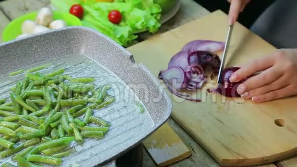 一个女人把切好的洋葱和绿豆放在锅里视频的预览图