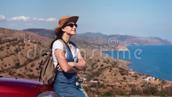 快乐轻松年轻的旅行女性在背景下的汽车顶上享受日光浴视频的预览图