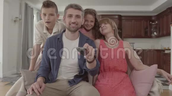 肖像快乐可爱的家庭一起在家看电视父亲拿着遥控器切换频道视频的预览图