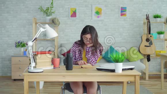 一个戴眼镜留着长发的漂亮亚洲女孩在现代住宅的客厅里看书用声音说话视频的预览图