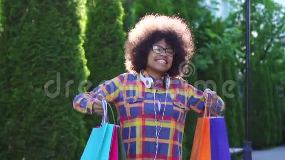 肖像画非洲女人留着非洲发型购物后带着包裹看着镜头慢悠悠视频的预览图