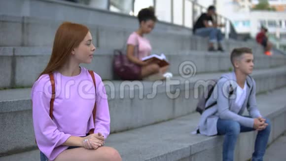 调情吸引人的少女女性看着英俊的男学生坐着楼梯视频的预览图