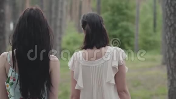 两个留着长发穿着短裙的美女背着篮子走在森林里慢动作视频的预览图