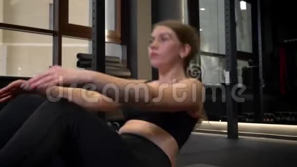 这张特写镜头拍摄的是一个精疲力尽的运动女孩她躺在健身房附近用手机做腹部仰卧起坐视频的预览图