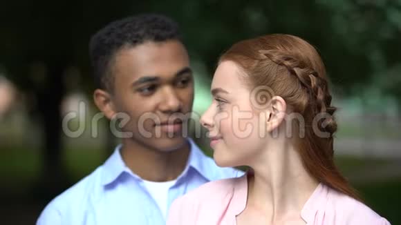 快乐的多种族青少年情侣在镜头前微笑第一次在公园约会爱视频的预览图