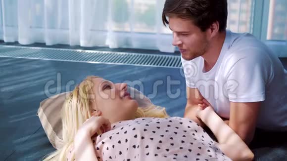 幸福的年轻情侣躺在阳光明媚的房间里亲吻视频的预览图