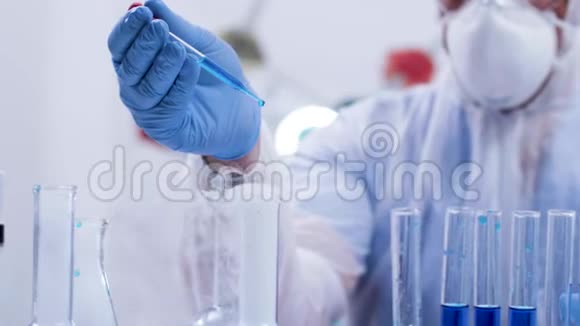 在一个研究实验室里用吸管在一种吸烟的蓝色液体上接近最科学的浇注试剂视频的预览图