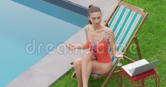 身着游泳服装在游泳池附近喝酒的女人视频的预览图