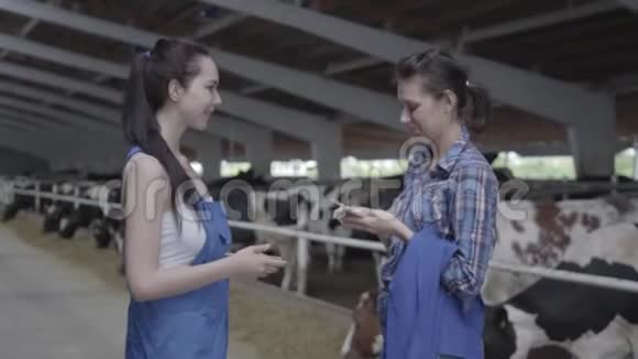 两个年轻漂亮的微笑女工在奶牛场分享金钱和握手积极的农民获得收入视频的预览图