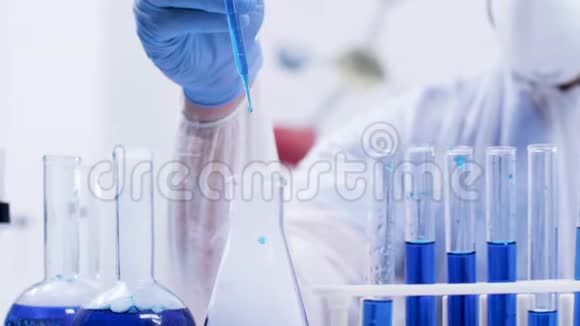 现代实验室中的女化学科学家用蓝色液体试管中的移液管视频的预览图