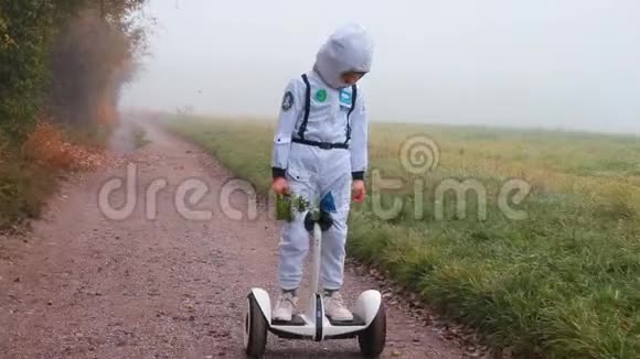 一个穿着宇航员服装的男孩骑着陀螺仪沿着地球上的一条路走视频的预览图