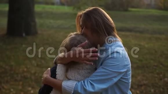 一位年轻的母亲和她的女学生晚上散步女孩温柔地拥抱在公园里母爱母亲视频的预览图