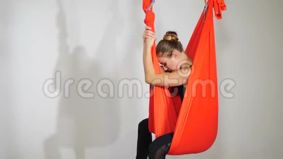 有氧反重力瑜伽在健身房年轻女子正在白色背景上练习瑜伽健身女运动员吊着视频的预览图