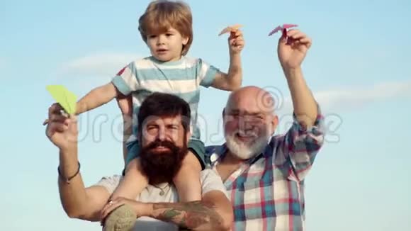 幸福的父亲给儿子捎带骑在他的肩膀和抬头童年概念家庭假日视频的预览图