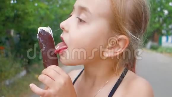 十几岁的女孩吃冰淇淋和巧克力糖霜在棍子上小美丽的女孩舔冰棒棒糖视频的预览图