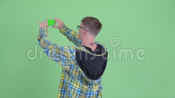 快乐书呆子男人用电话拍照的后视图视频的预览图