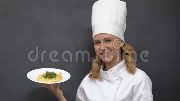 快乐的女厨师拿着盘子带着意大利面和微笑邀请到餐厅视频的预览图