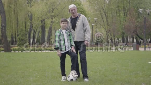 一幅小男孩穿着格子衬衫的肖像一个积极的老人看着公园里的摄像机孙子视频的预览图
