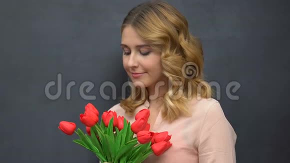 一位漂亮的女士拿着一束郁金香在黑板隔离过敏视频的预览图