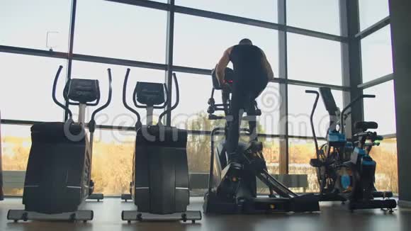 在健身房的有氧运动区域一名男子乘坐椭圆训练机后景视频的预览图