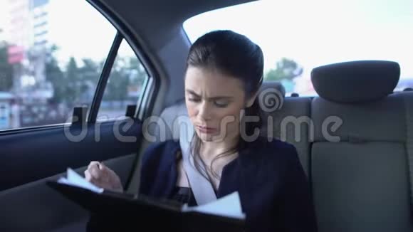 穿着西装的疲惫的女人看着文件觉得坐在车里偏头痛视频的预览图