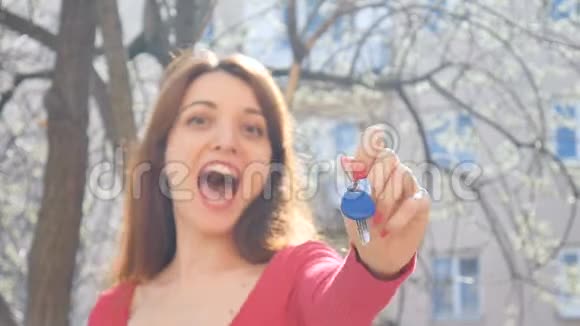 情绪化的年轻女孩拿着钥匙带着幸福和兴奋的蓝色钥匙链带红色指甲的女性手视频的预览图