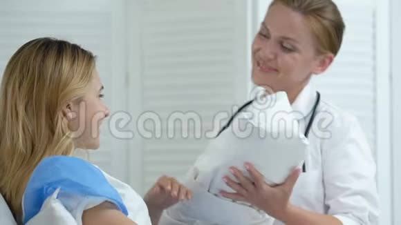 快乐的医生把新生儿交给床上的年轻母亲产妇保健视频的预览图