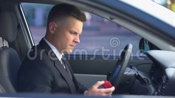 怀疑男性拿着订婚戒指的盒子坐在车里感觉不确定视频的预览图