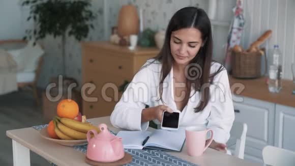 女孩坐在厨房的桌子上拿着橘子闻着慢动作视频的预览图
