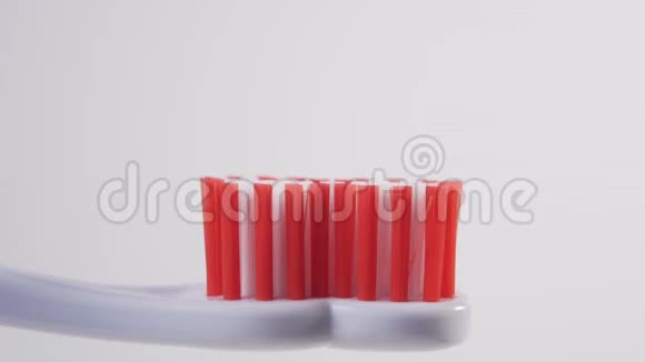 一个男人从白色的管子里把一支蓝色的牙膏挤到塑料牙刷的红色刚毛上视频的预览图