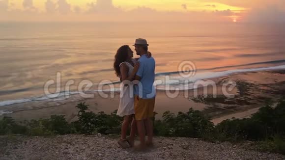 情侣拥抱在夕阳和海洋背景下接吻慢动作视频的预览图