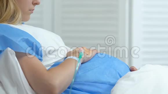 病态孕妇抚摸腹部躺在病床上孕期健康问题视频的预览图