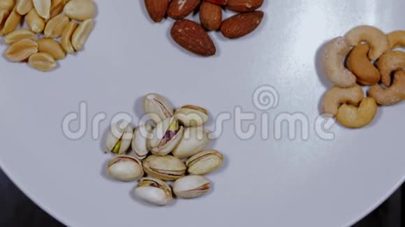 不同种类的坚果在白色的菜肴上可以看到杏仁皮茶腰果花生榛子干水果视频的预览图