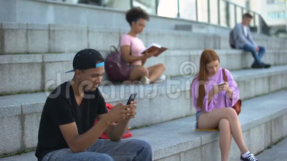 快乐的青少年在户外聊天智能手机高中生休息视频的预览图