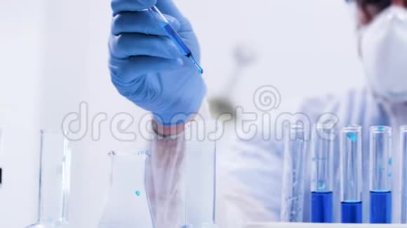 药剂师用移液管在活性蓝色液体中灌注溶液的特写镜头视频的预览图