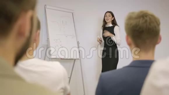 漂亮的年轻女子穿着正式服装在办公室讲课站在办公室董事会附近的人面前商务视频的预览图