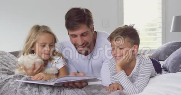 父亲带着他的孩子在卧室里读故事书视频的预览图