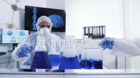 从实验室里的移动推车上取出蓝色液体的盖达尔设备的科学家视频的预览图