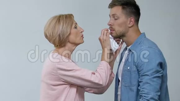 关爱的老母亲擦着儿子的嘴困惑的妻子摸着头过度保护视频的预览图