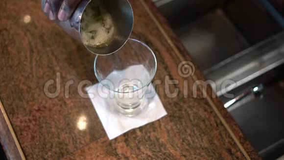 酒保把一杯酒精饮料从柜台上的摇床上倒入玻璃杯中海洋中的性鸡尾酒视频的预览图