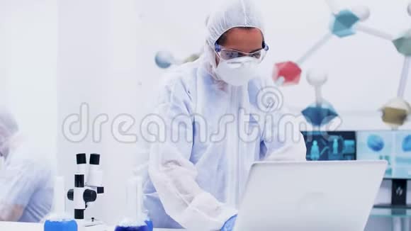 女科学家站起来在一个现代化的化学实验室里在电脑上打字视频的预览图
