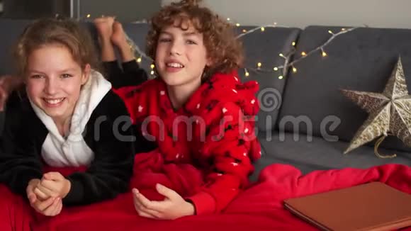 孩子们穿着睡衣一男一女躺着拥抱平安夜驯鹿睡衣圣诞装饰品和花环视频的预览图