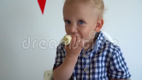 有趣的孩子儿子吃香蕉笑着看着相机向后移动视频的预览图