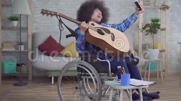 残疾的非裔美国妇女一个头发是非洲的坐在轮椅上用吉他自拍视频的预览图