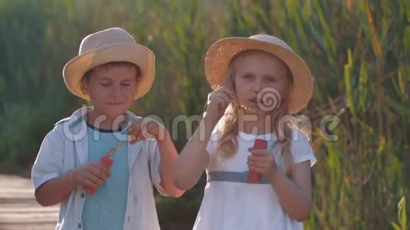 儿童游戏有趣可爱的孩子戴着草帽的男孩和女孩在露天吹泡泡和大笑视频的预览图
