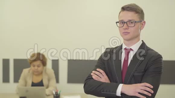 一个戴着眼镜穿着漂亮西装充满自信的年轻人的画像他双臂交叉在镜头中视频的预览图