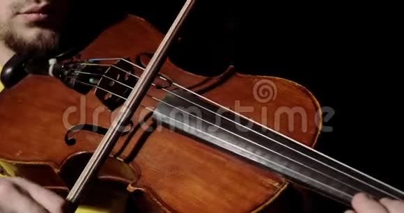 男子小提琴演奏在ALT与弓在黑色背景乐器特写视频的预览图