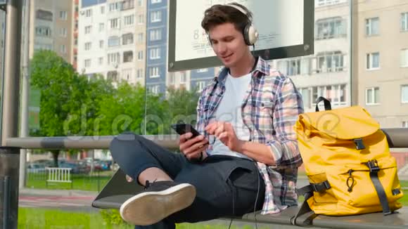 夏天男人坐在长凳上背着一个黄色的背包现代街头风格视频的预览图
